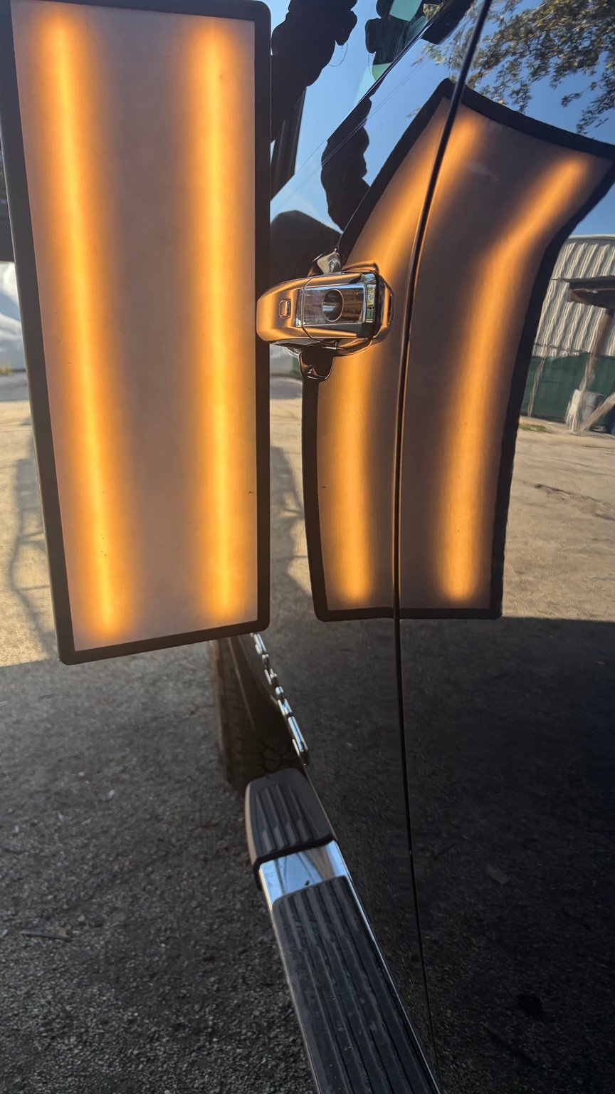 Door panel after paintless dent repair, photographed with a repair light