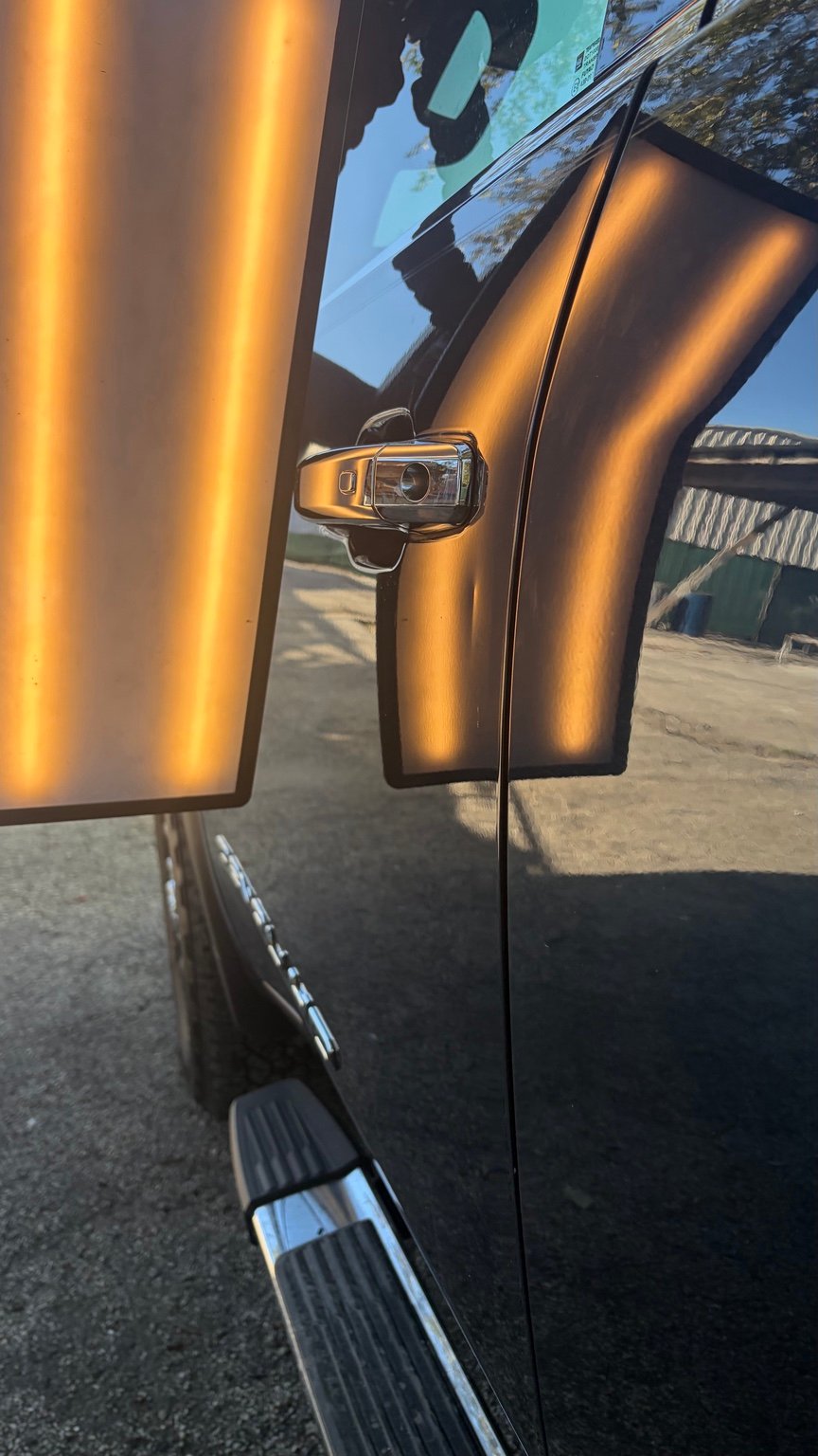 Door panel before paintless dent repair, photographed with a repair light