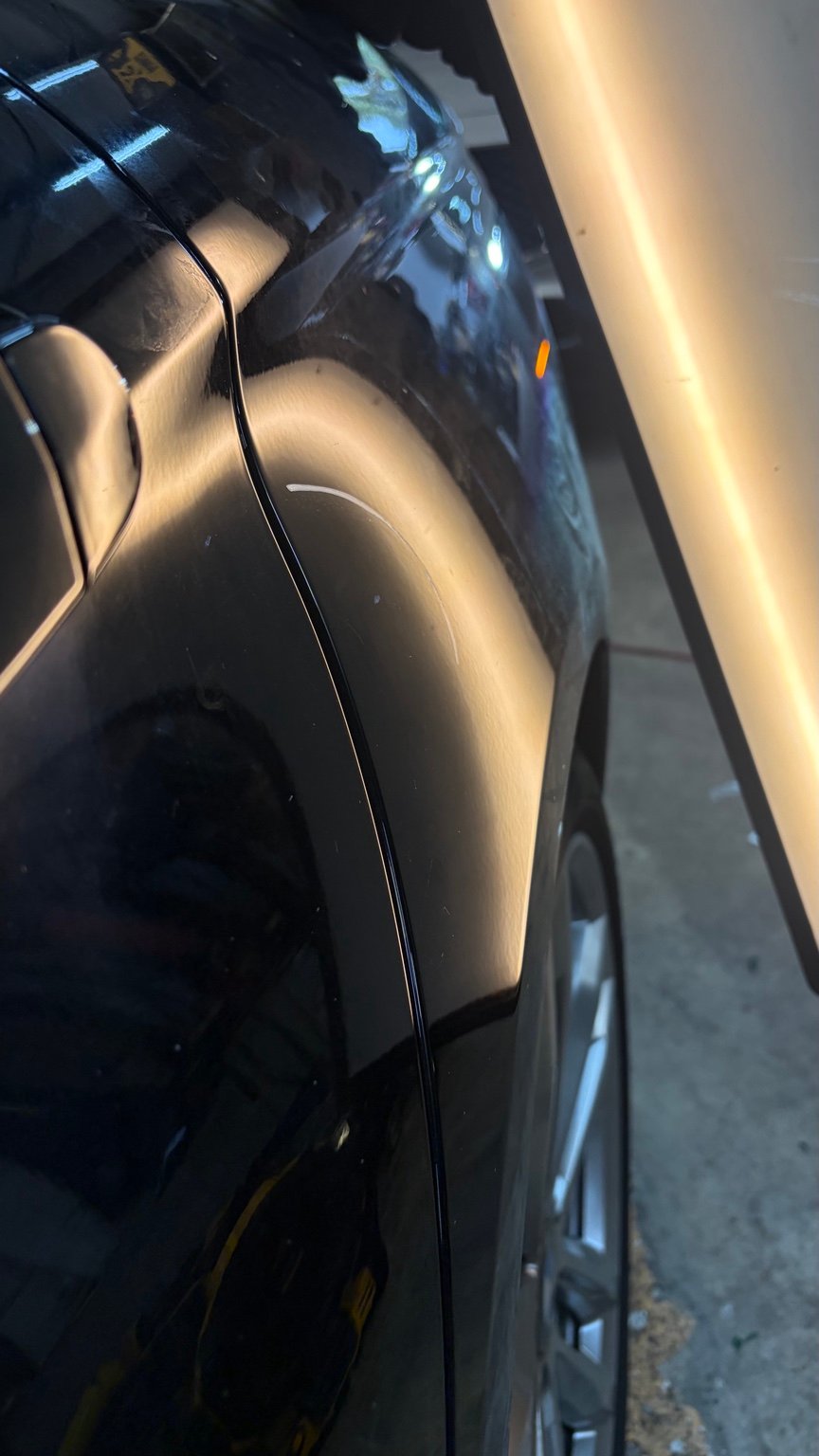 Fender panel after paintless dent repair, photographed with a repair light